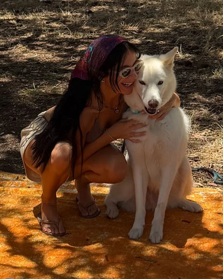 A team member hugging her white shepherd mix on a picnic blanket