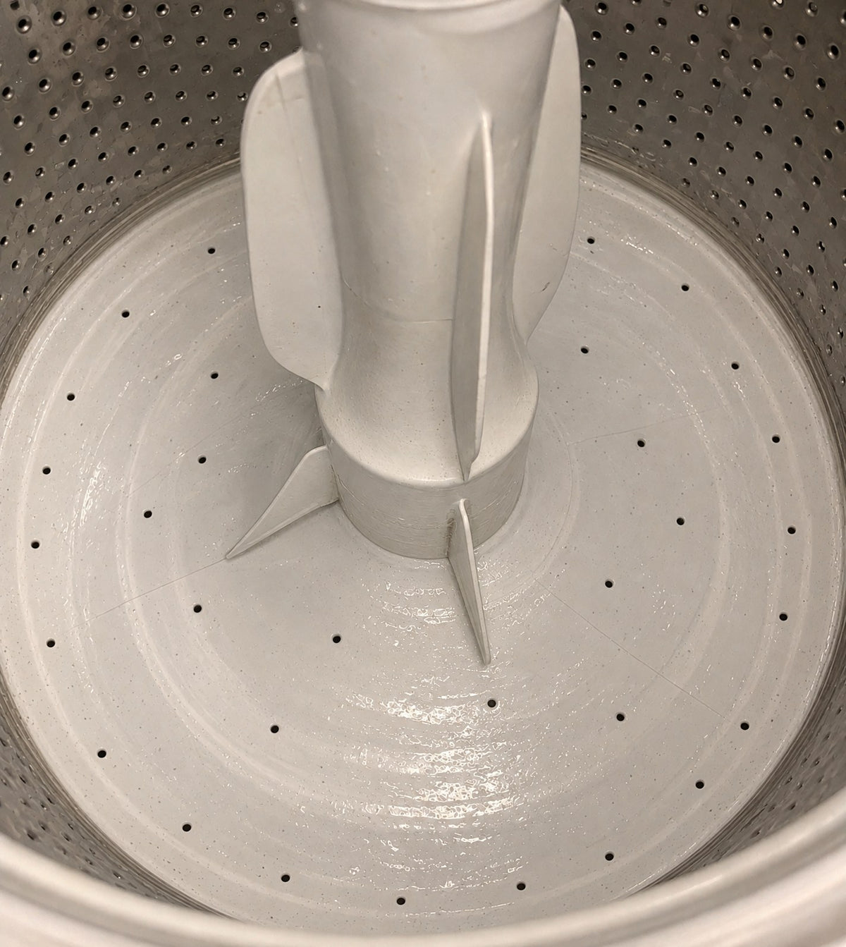 Illustration of the same top-loading washer tub floor without the detergent residue, after