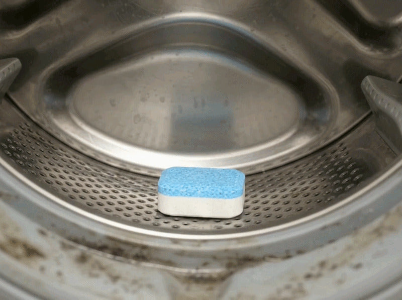 An X-All tablet dropping into an empty washer drum